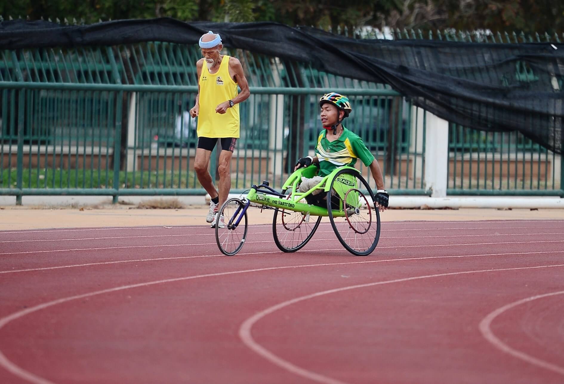 Sur une piste d’athlétisme, 2 coureurs, l’un d’un âge vénérable, l’autre en fauteuil roulant sport